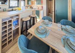 A modern kitchen with a wooden countertop, bar stools, and a dining table set for four. - 3 bedroom accommodation in Colchester (Colchester)