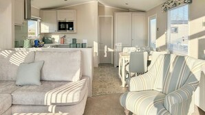 A living room with a sofa, armchair, and a dining area with a table and chairs.