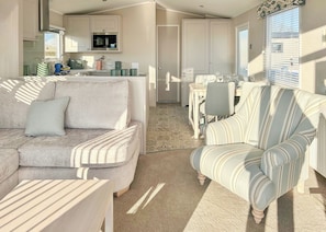 A living room with a sofa, armchair, and a dining area with a table and chairs.