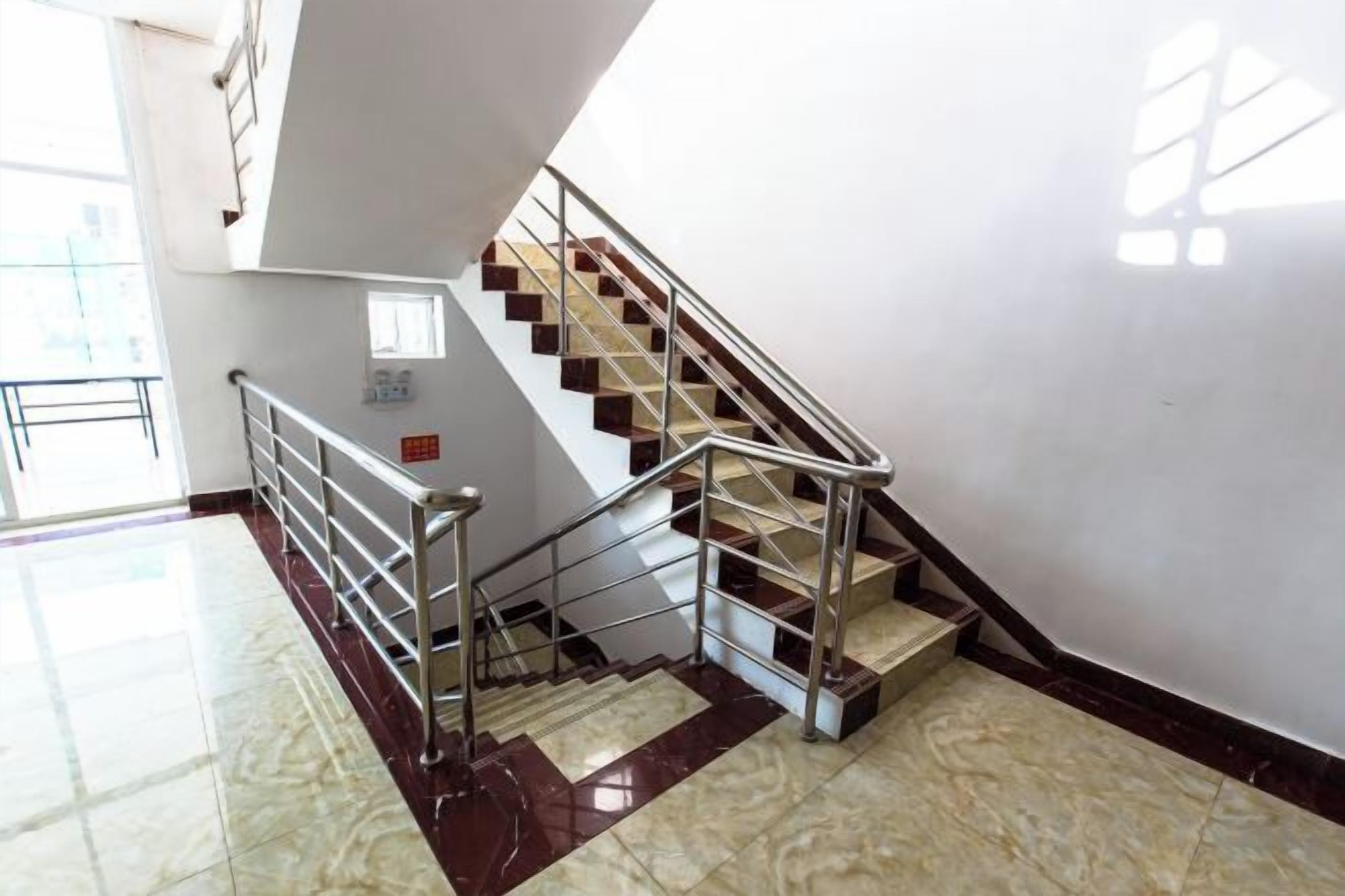 A staircase with metal railings and marble flooring, leading to an upper level.