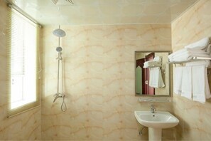 Un baño con ducha, lavamanos y toallero.