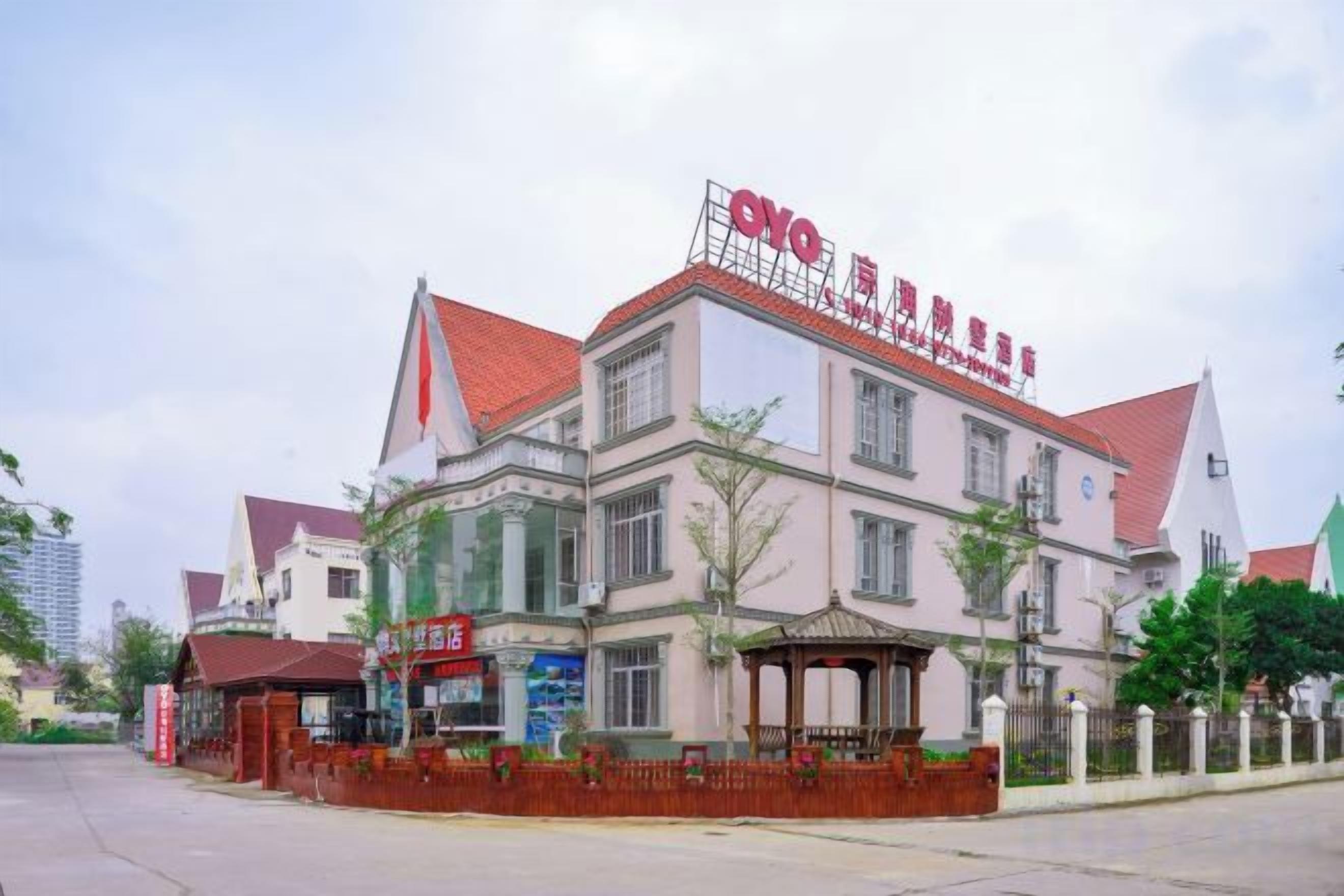 A multi-story building with a red roof and signage indicating it is a hotel.