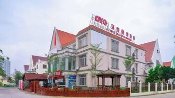 A multi-story building with a red roof and signage indicating it is a hotel.