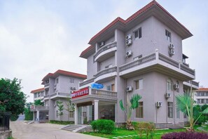 Een meerlaags hotel met balkons, airconditioners en een bord waarop een restaurant wordt aangegeven.