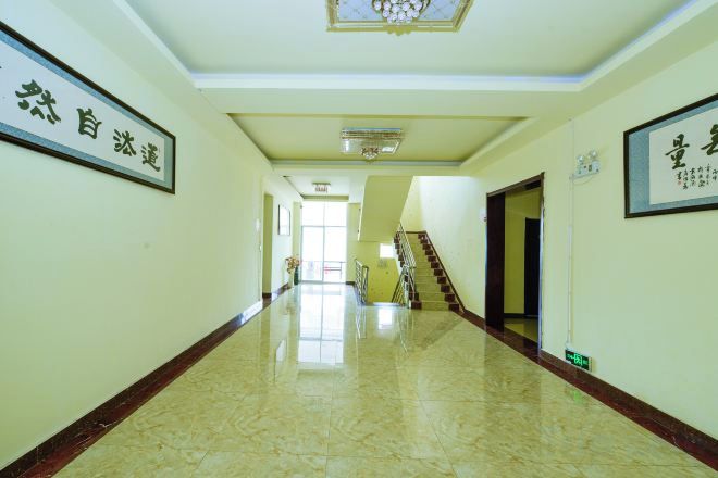 A corridor with a polished floor, a staircase, and framed calligraphy on the walls.