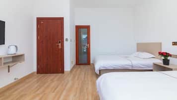 Ein Hotelzimmer mit zwei Betten, Holzboden, einer kleinen Ablage mit Wasserkocher und einer Holztür.