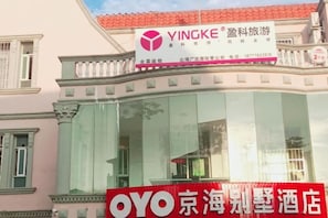 A hotel building with a large glass facade and a sign for 'YINGKE' above the entrance. - OYO Beihai Jinghai Villa (Yintan) (Beihai)