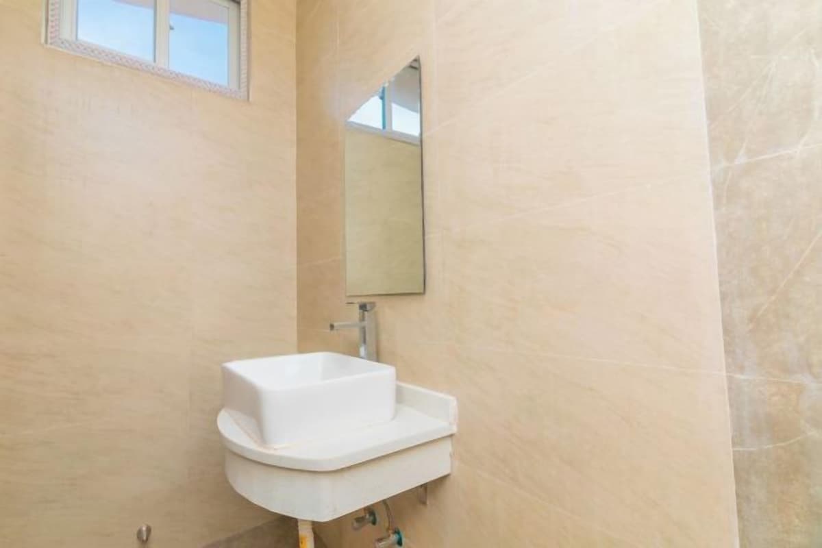 A bathroom with a white sink, a mirror, and beige walls.