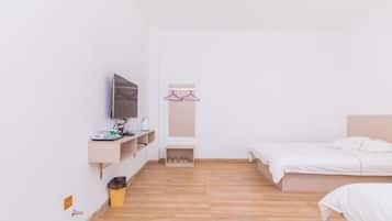 Ein schlicht eingerichtetes Schlafzimmer mit einem Bett, einem Fernseher, einem Regal mit Pflegeprodukten und einer kleinen Mülltonne.