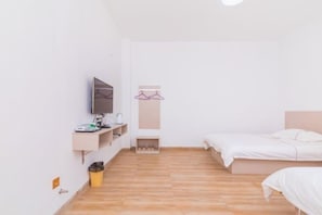 A minimalist bedroom with a bed, a TV, a shelf with toiletries, and a small trash bin. - OYO Beihai Jinghai Villa (Yintan) (Beihai)