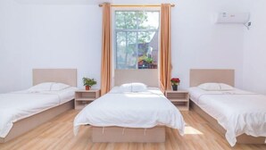 A room with two single beds, a window with curtains, an air conditioning unit, and a small plant on the nightstand. - OYO Beihai Jinghai Villa (Yintan) (Beihai)