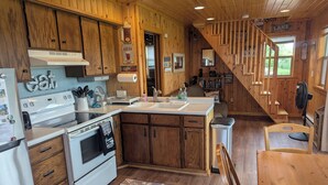 A wooden cabin-style kitchen with a stove, oven, sink, and wooden cabinets.