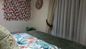 Ein Schlafzimmer mit einem Bett, einer Zierleiste an der Wand, einem Spiegel und einem Fenster mit Vorhängen.
