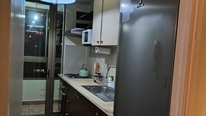 Eine kleine Küche mit Kühlschrank, Mikrowelle und Spüle.