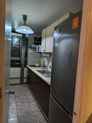 A compact kitchen with a refrigerator, microwave, and a sink.