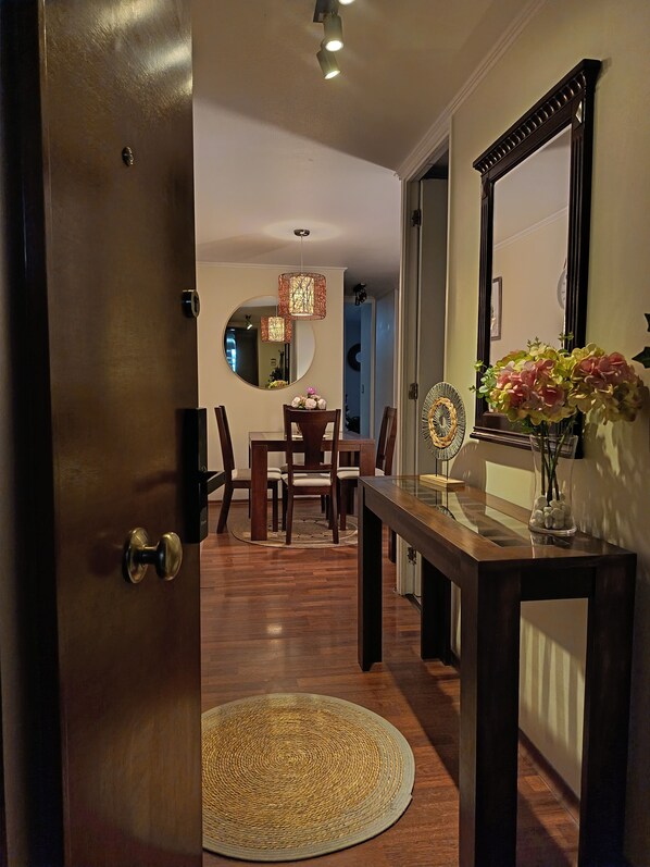A wooden door leading to a dining area with a round table, chairs, and a mirror on the wall.