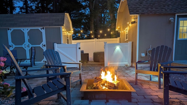 A backyard with a fire pit, outdoor seating, and string lights. - Tiny, Funky, and Full of Love - Welcome to the Love Shack (Piney Point)