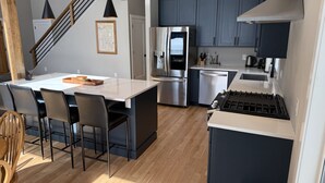 A modern kitchen with a central island, stainless steel appliances, and a dark cabinetry theme. - Serendipity North Three Lakes (Three Lakes)