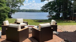 Outdoor wicker furniture with cushions, a fire pit, and a view of a lake. - Serendipity North Three Lakes (Three Lakes)