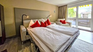 Een hotelkamer met een groot bed, een bank, een bureau en uitzicht op de omgeving.