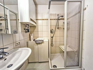 Une salle de bain équipée d’un lavabo, d’un miroir, d’un porte-serviettes, d’une douche et de toilettes.