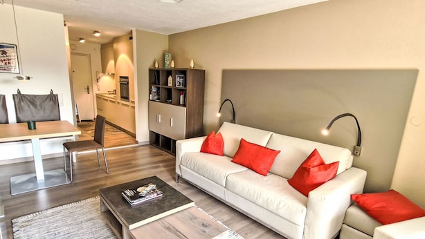 Een moderne woonkamer met een bank, salontafel en een eethoek met stoelen en een tafel.