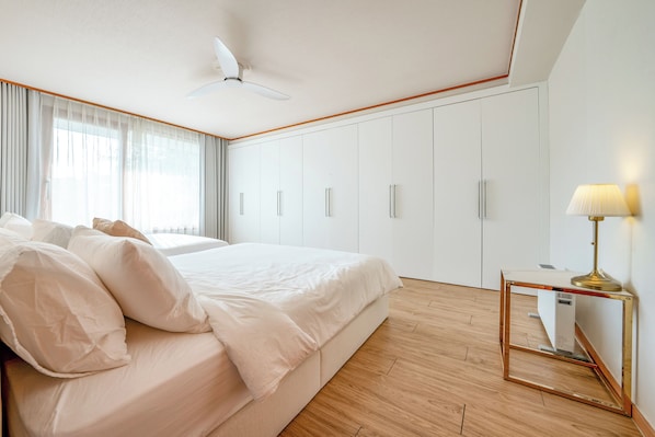 Une chambre à coucher comprenant un lit, un ventilateur de plafond, une table de chevet avec une lampe et une armoire.