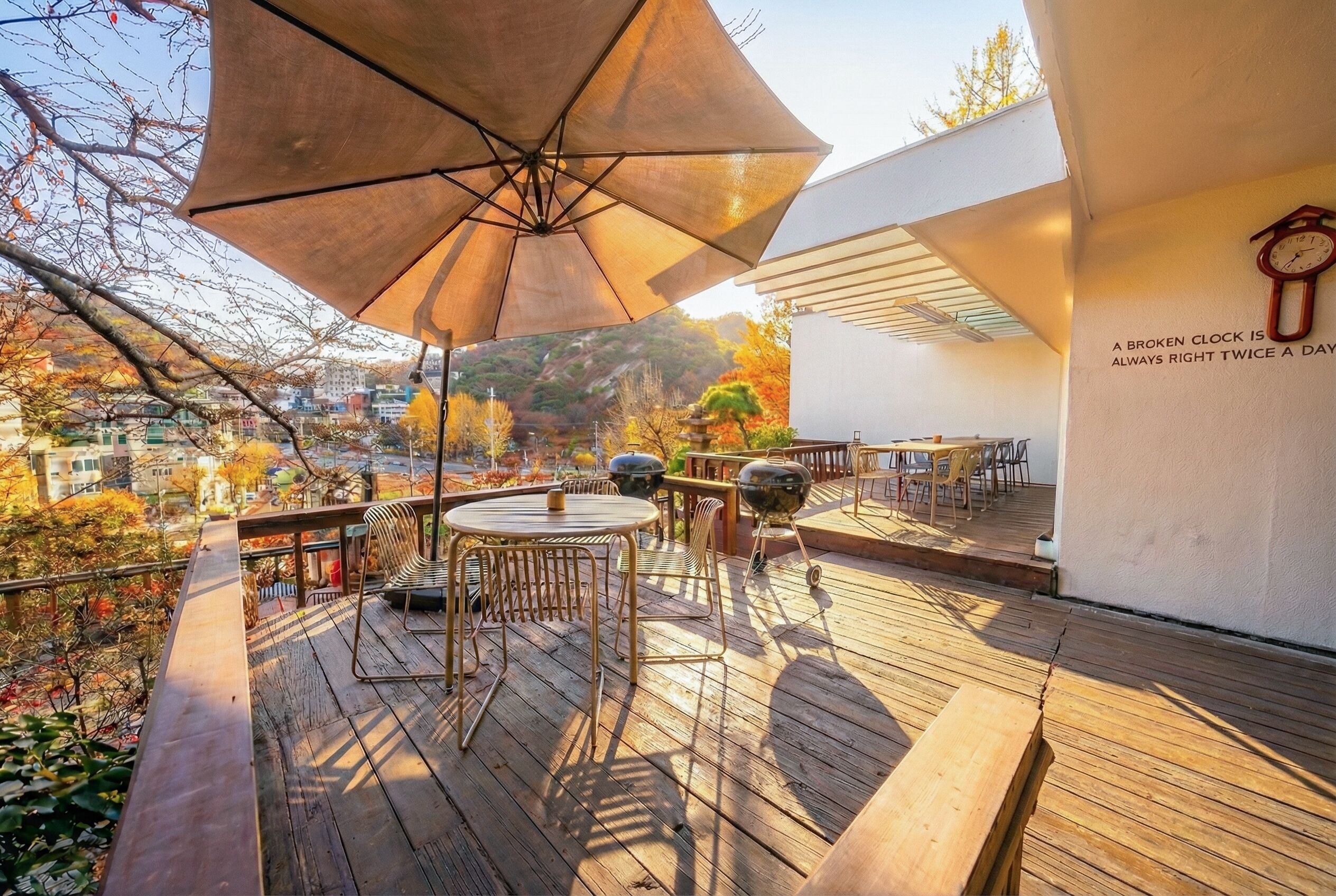 A wooden deck with outdoor seating, a barbecue grill, and a large umbrella.