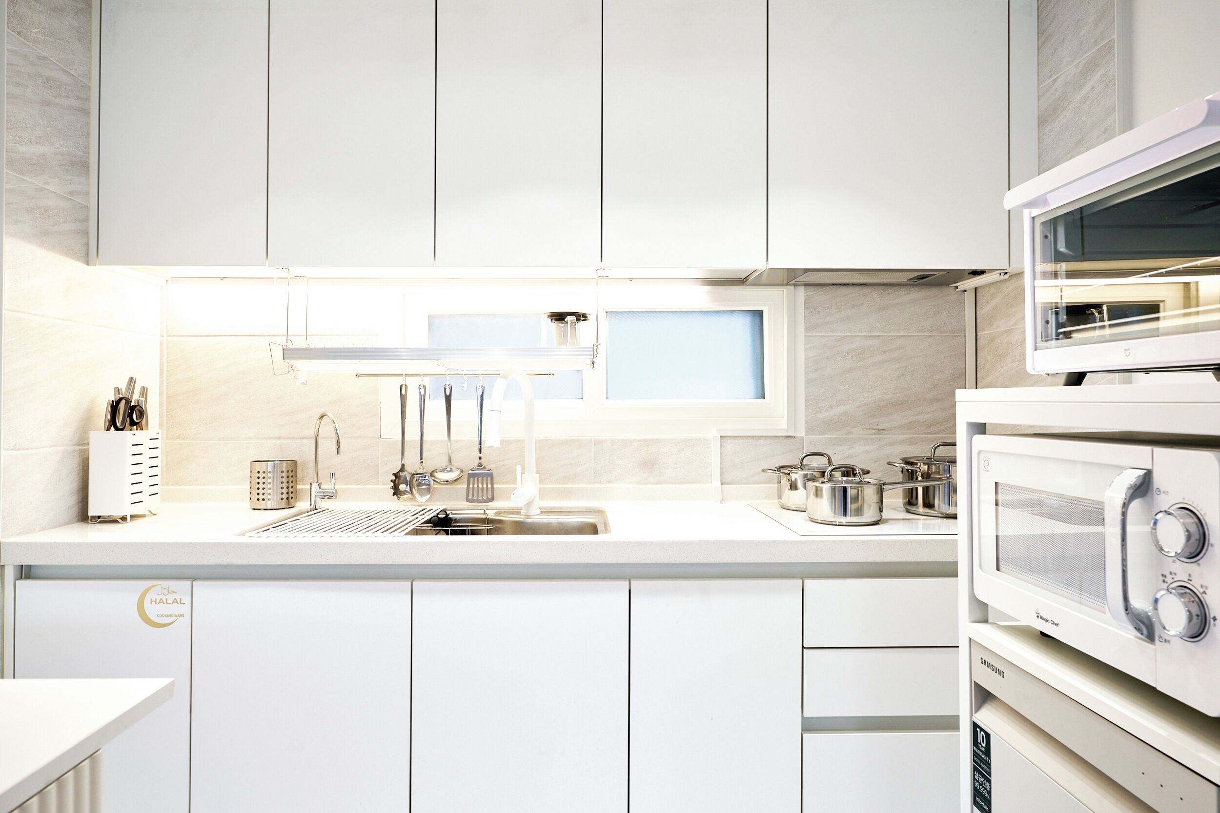 A modern kitchen with white cabinetry, a stainless steel sink, and a built-in microwave.