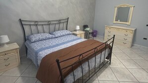 A bedroom with a bed, bedside tables, a dresser, a mirror, and a plain wall. - Safe Refuge, accommodation outside the city chaos with luggage storage (Macerata Campania)