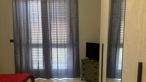 A bedroom with a bed, a dresser, and a TV. - Safe Refuge, accommodation outside the city chaos with luggage storage (Macerata Campania)