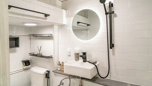 Een moderne badkamer met een wit wastafelmeubel, een ronde spiegel en een handdouche.