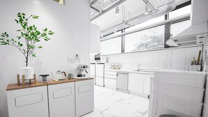 A modern kitchen with white cabinetry, a marble floor, and a potted plant.