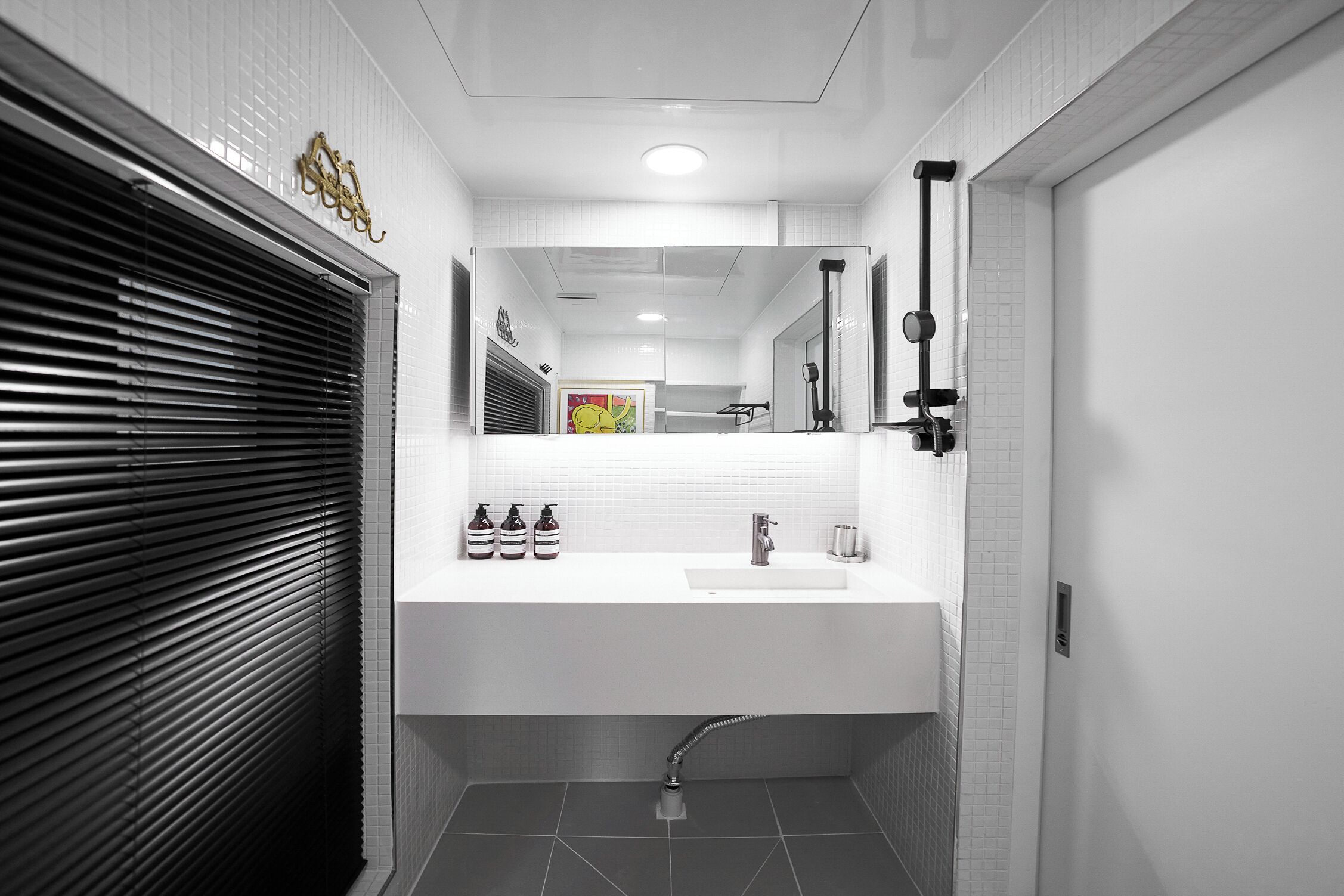Un bagno moderno con lavandino, specchio e doccia bianchi.