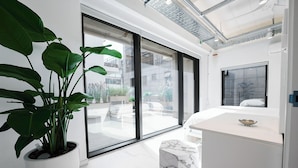 A modern bathroom with a marble sink, a potted plant, and a large window.