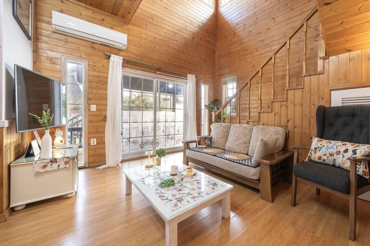Una habitación acogedora estilo cabaña con interior de madera, un sofá, una silla, una mesa de centro y un televisor.