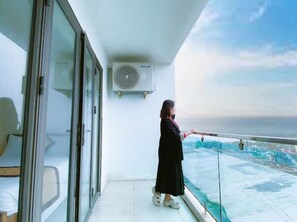 A balcony with a glass railing, a person standing, and a view of the sea. - Kinh Bac Hotel Hai Tien (Hoang Thanh)