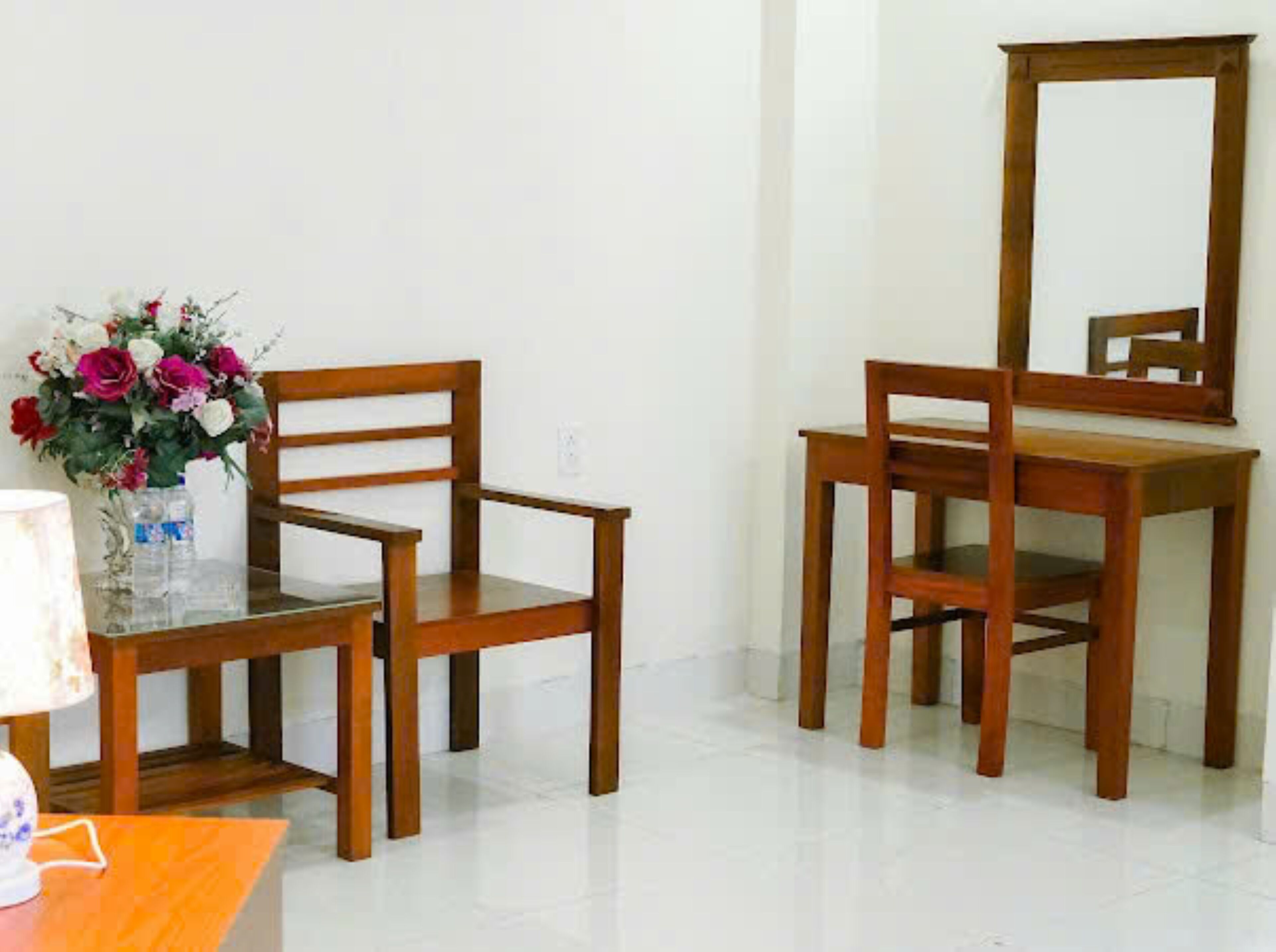 A room with a wooden chair, a wooden table, and a mirror on the wall.