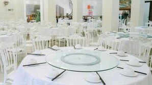 A banquet hall with round tables set for a formal event, surrounded by white chairs. - Kinh Bac Hotel Hai Tien (Hoang Thanh)