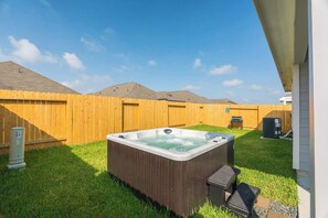 Ein Garten mit Whirlpool, Holzzaun und Rasenfläche.