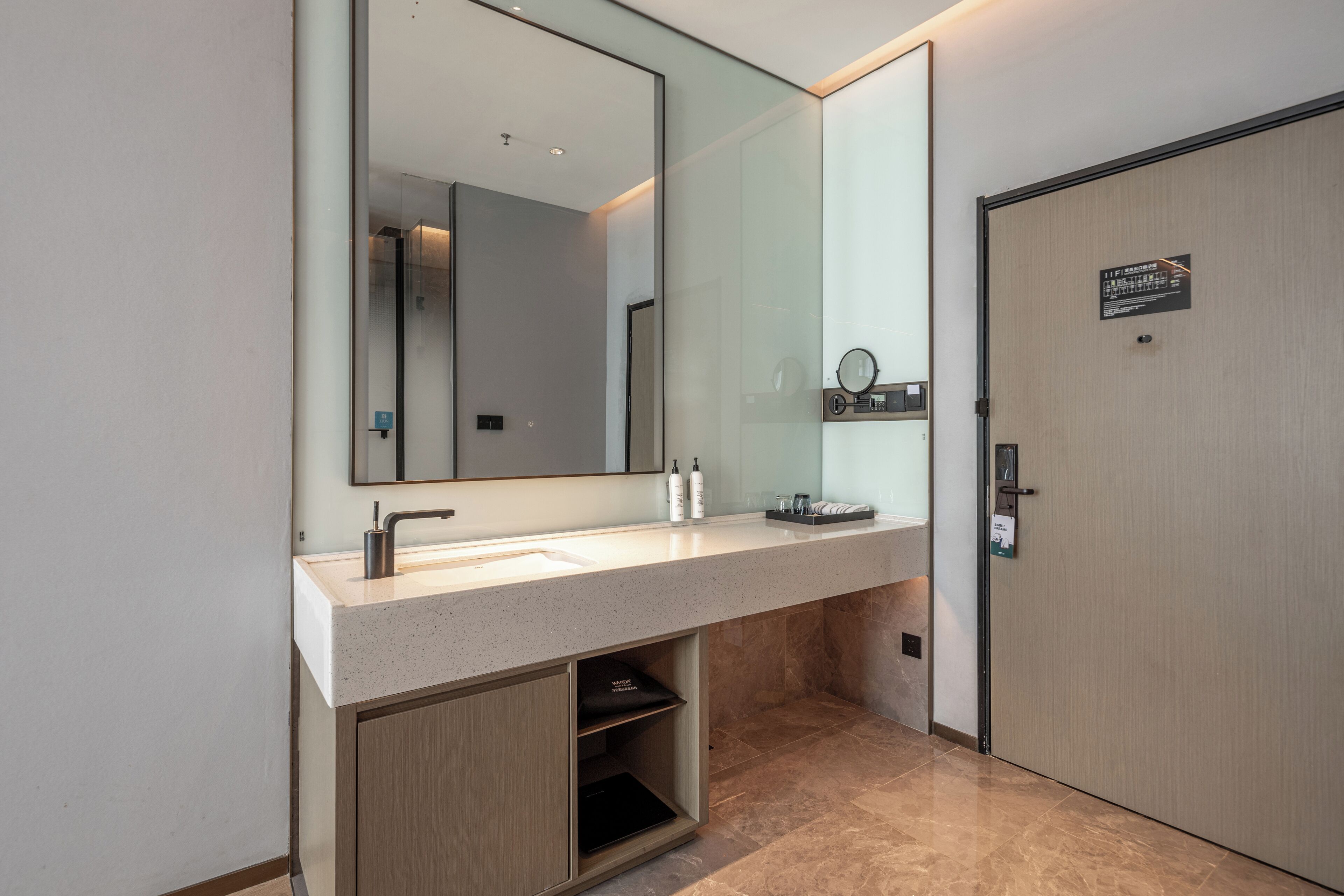 Un baño moderno con un espejo grande, un lavabo y una puerta con un letrero.