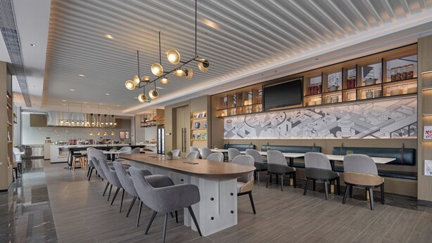 Un restaurante moderno con barra central, varias zonas de estar y un techo decorativo.