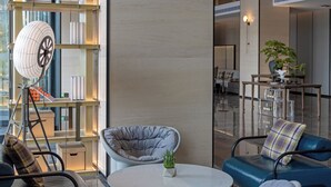 Un interior moderno con una zona de estar que incluye una mesa redonda, dos sofás y una estantería con objetos decorativos.