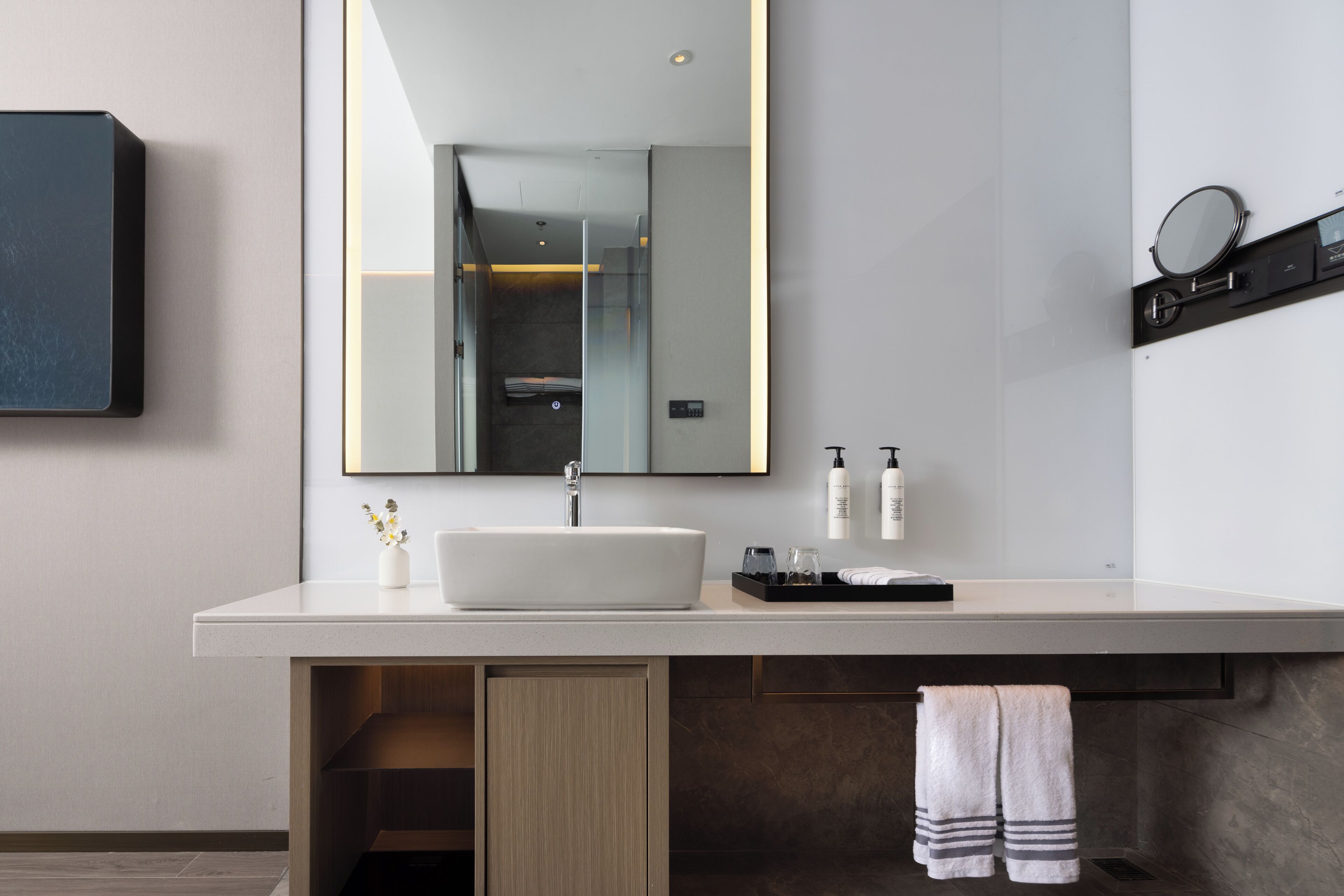 Un baño moderno con un espejo grande, lavamanos blanco y un toallero con toallas.