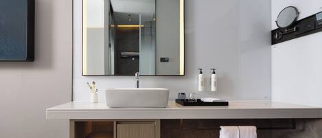 Un baño moderno con un espejo grande, lavamanos blanco y un toallero con toallas.