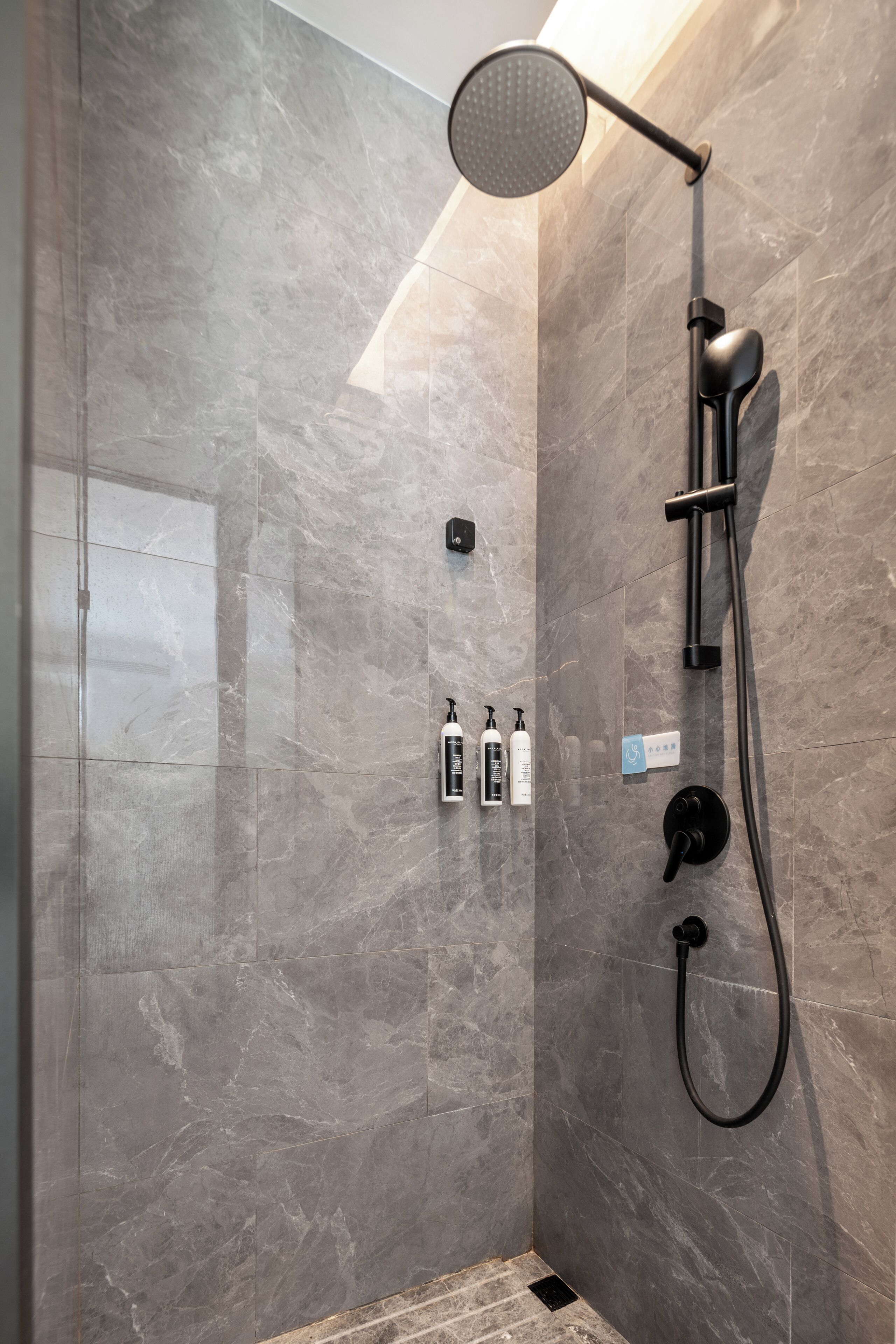 A modern shower with a handheld showerhead, a wall-mounted control panel, and a handheld shower attachment.