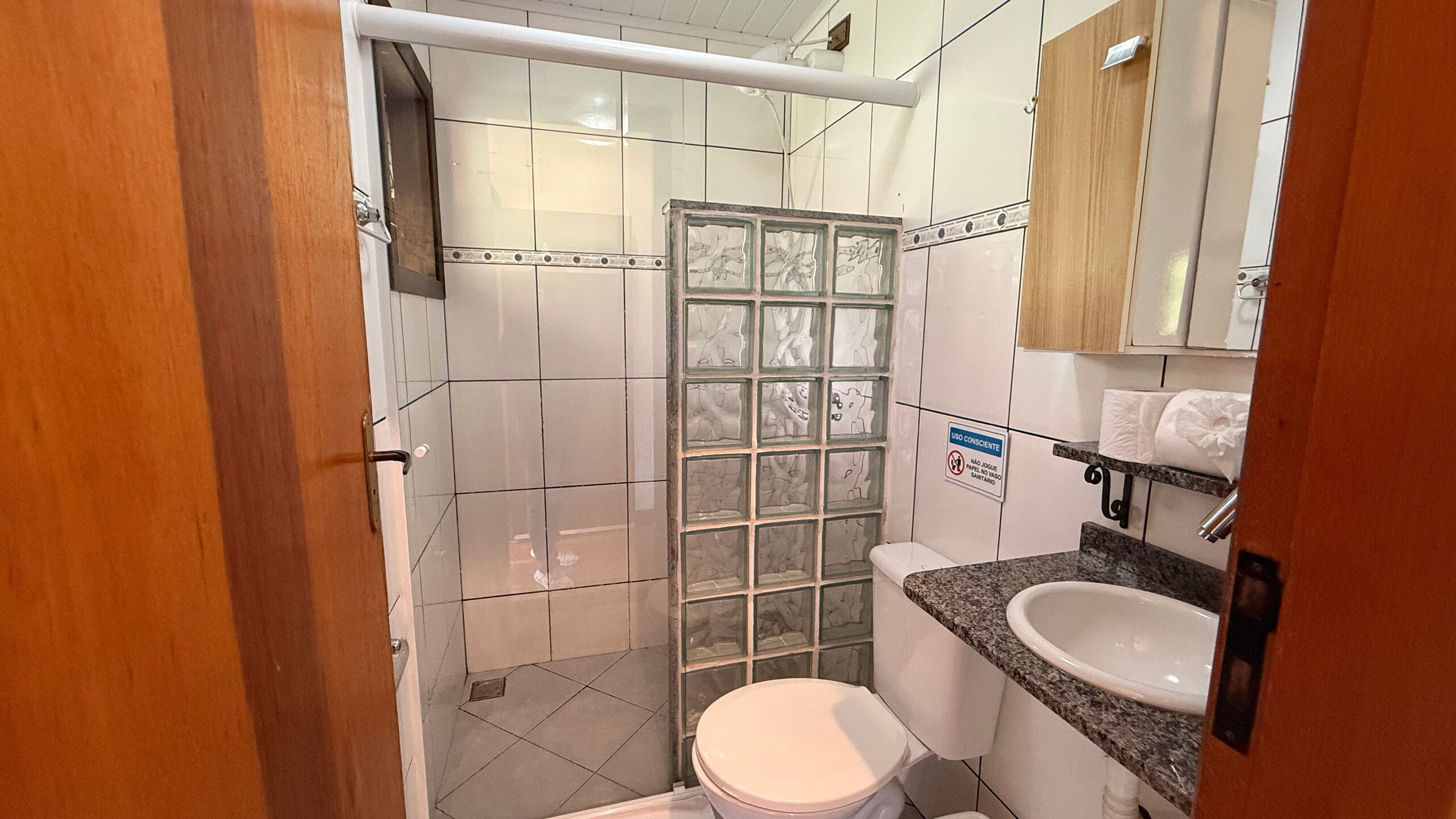 A small bathroom with a toilet, a sink, and a shower stall.