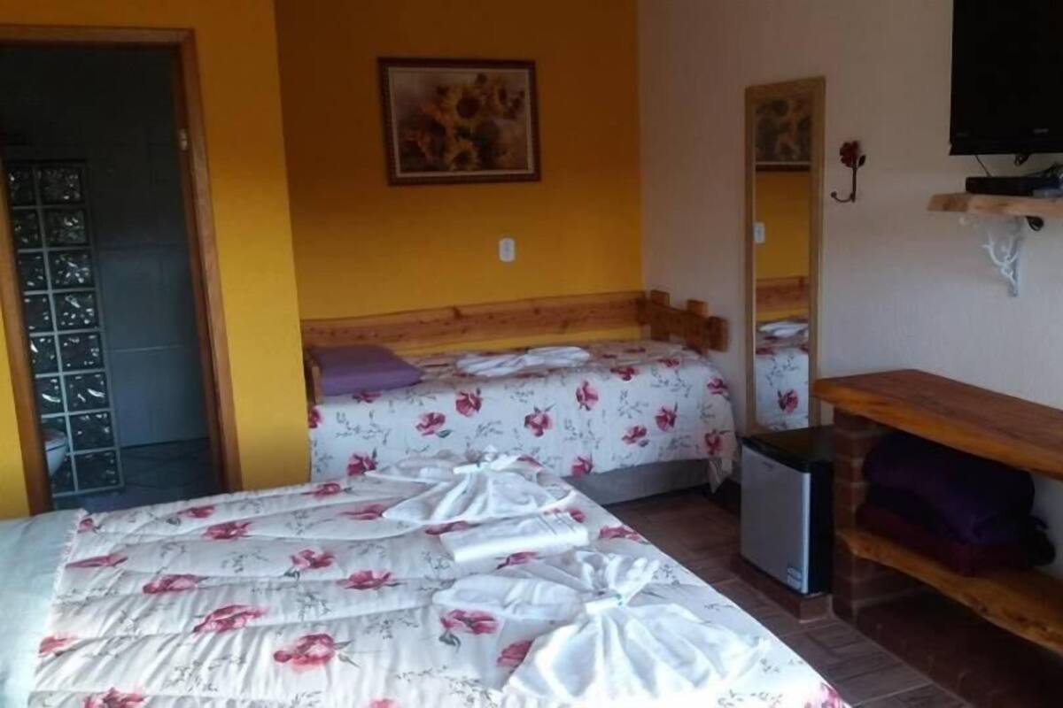 A bedroom with a bed, a small desk, a television, and a mirror.