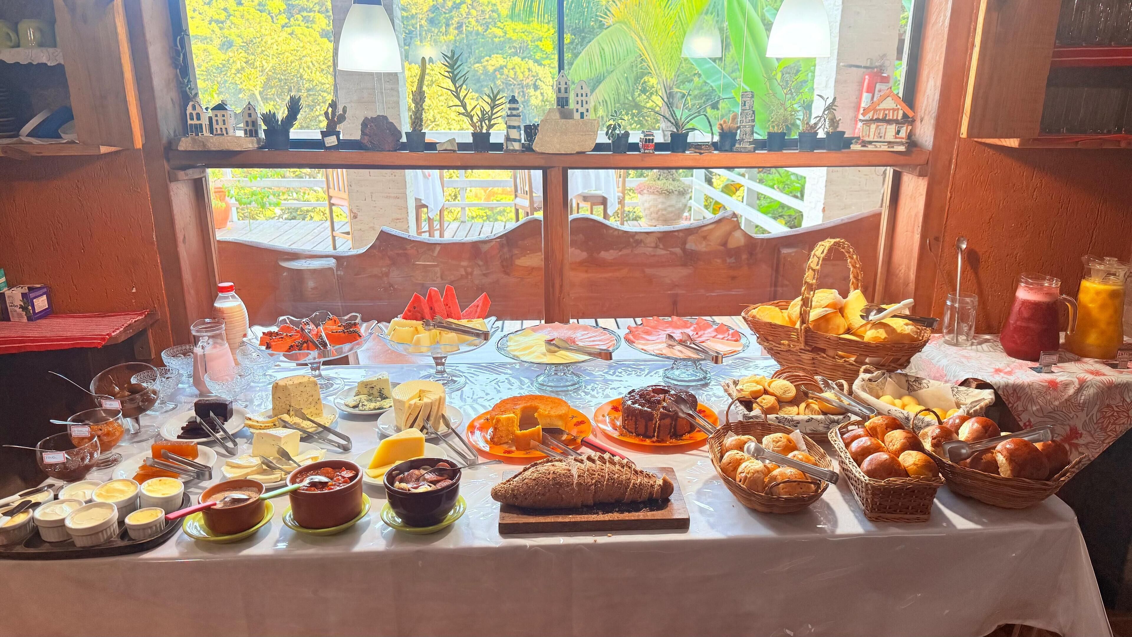 A buffet table with various food items and a view of a tropical landscape through a window.