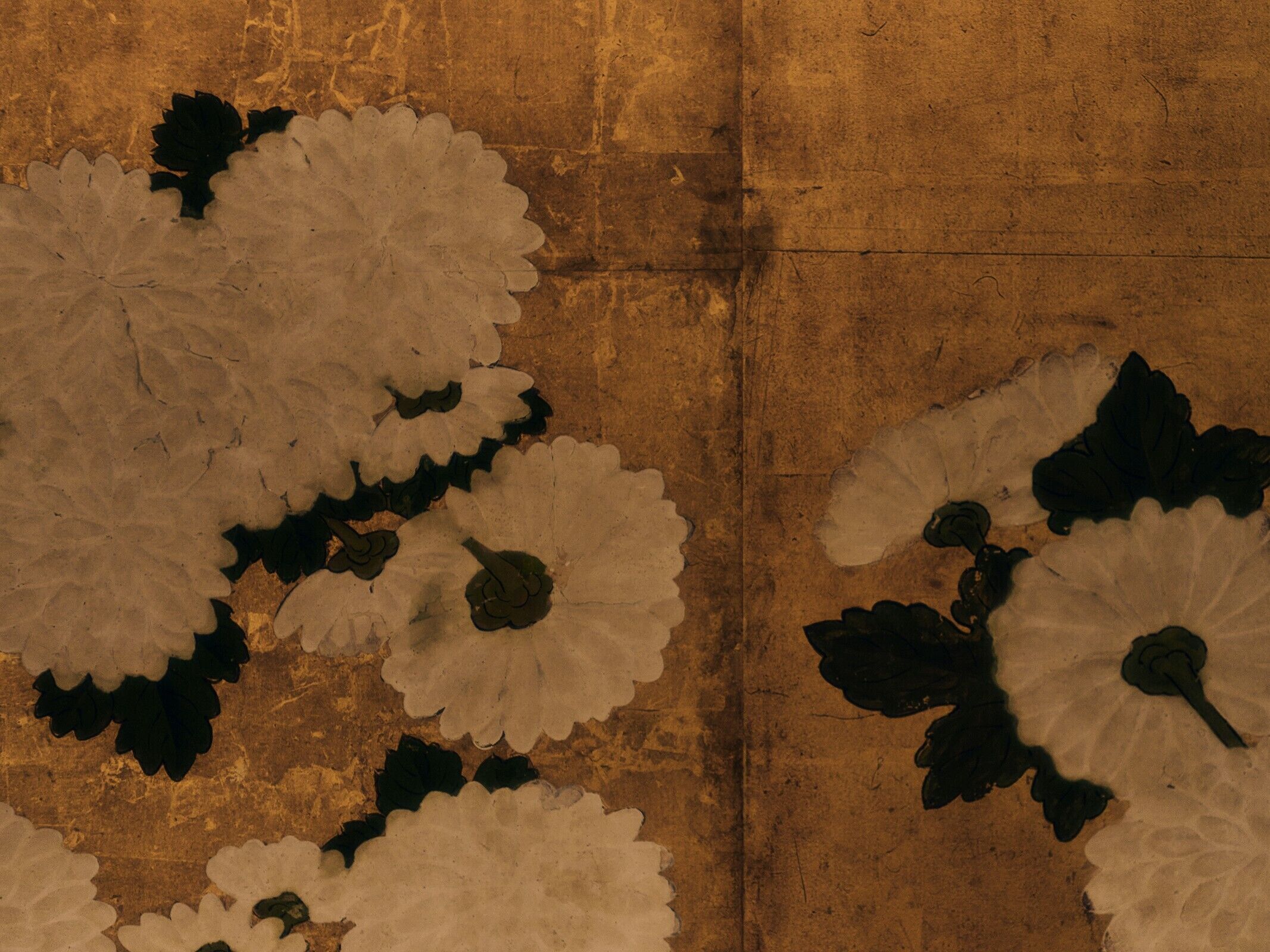 Una pared con textura y un diseño de formas blancas y verde oscuro que recuerdan a flores o hojas.
